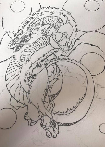 a black and white ink drawing in a sketchbook of an asian dragon with orbs. It is unfinished
